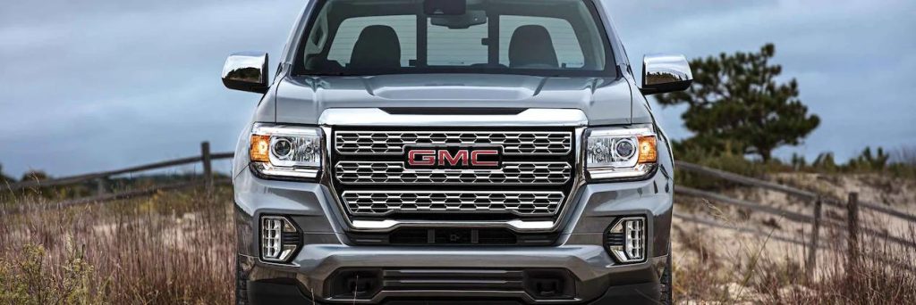 Silver 2022 GMC Canyon front-facing, baring its grills, on a field.