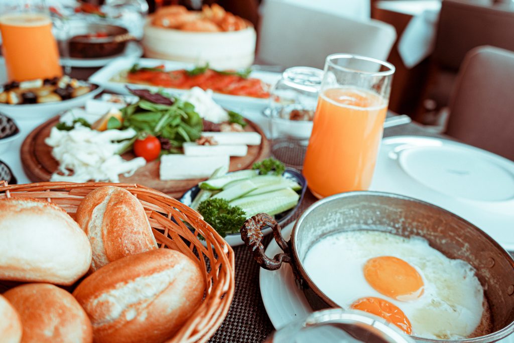 A table set with several breakfast foods and delicious orange juice, or perhaps, a mimosa.
