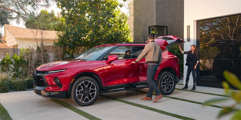 A red 2023 Chevrolet Blazer parked in a family's driveway as they finish packing the car to get in.