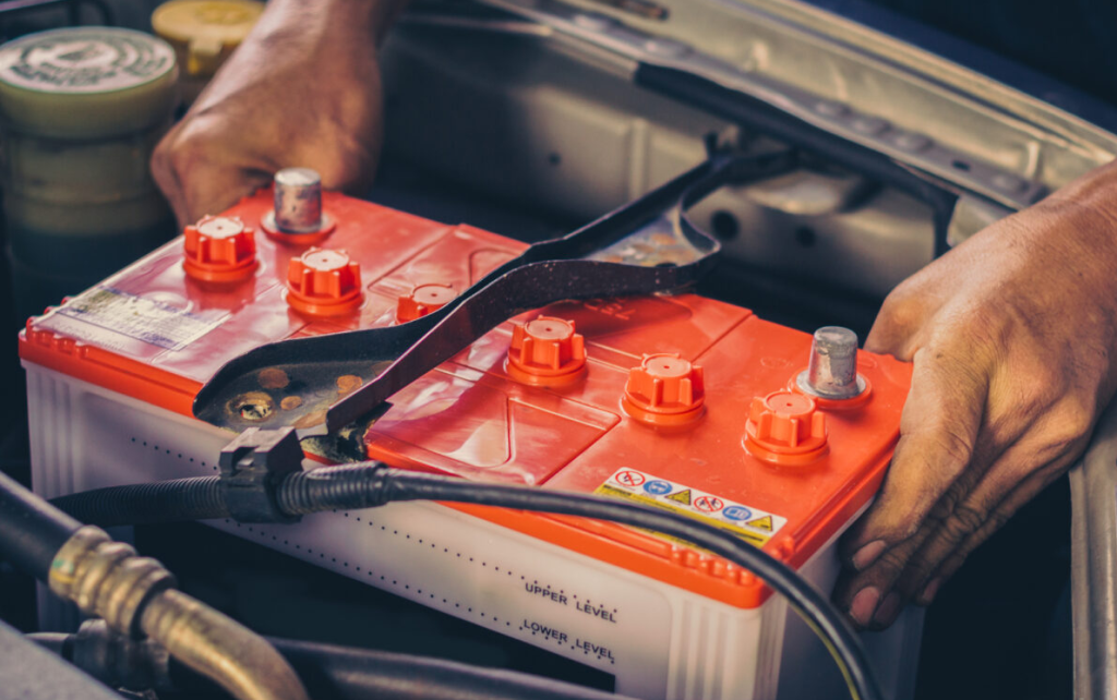 An auto repair technician replacing a car battery.